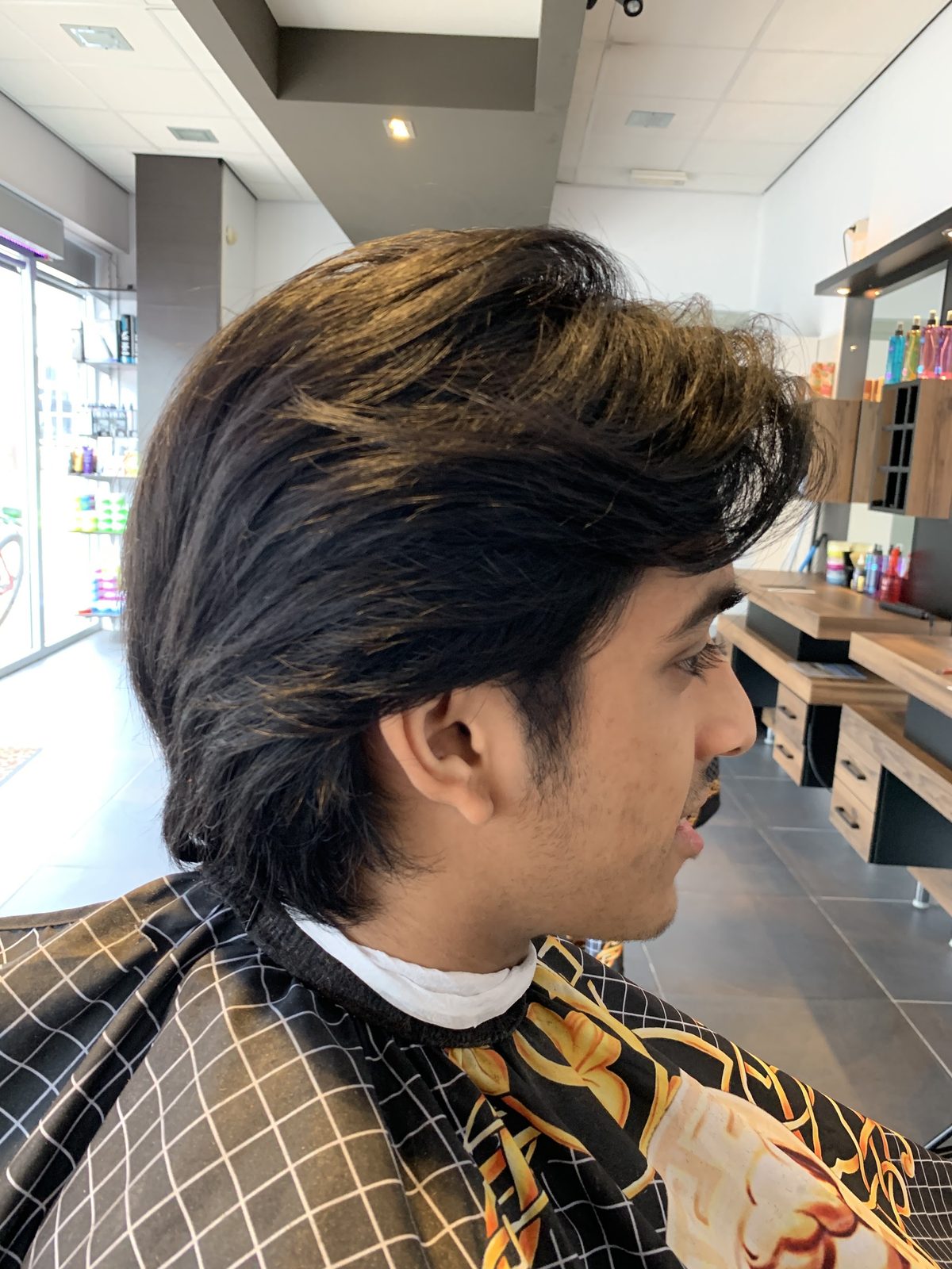 Lang donker haar net geknipt, met de winkelpui van de zaak op de achtergrond