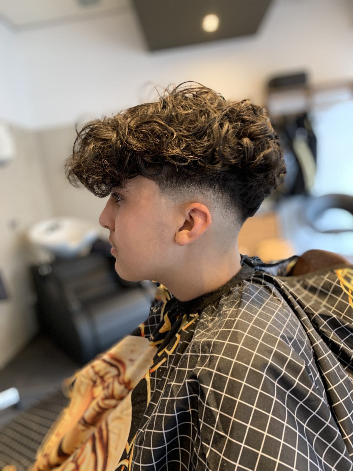 Krullend haar met een hoge fade aan de zijkant